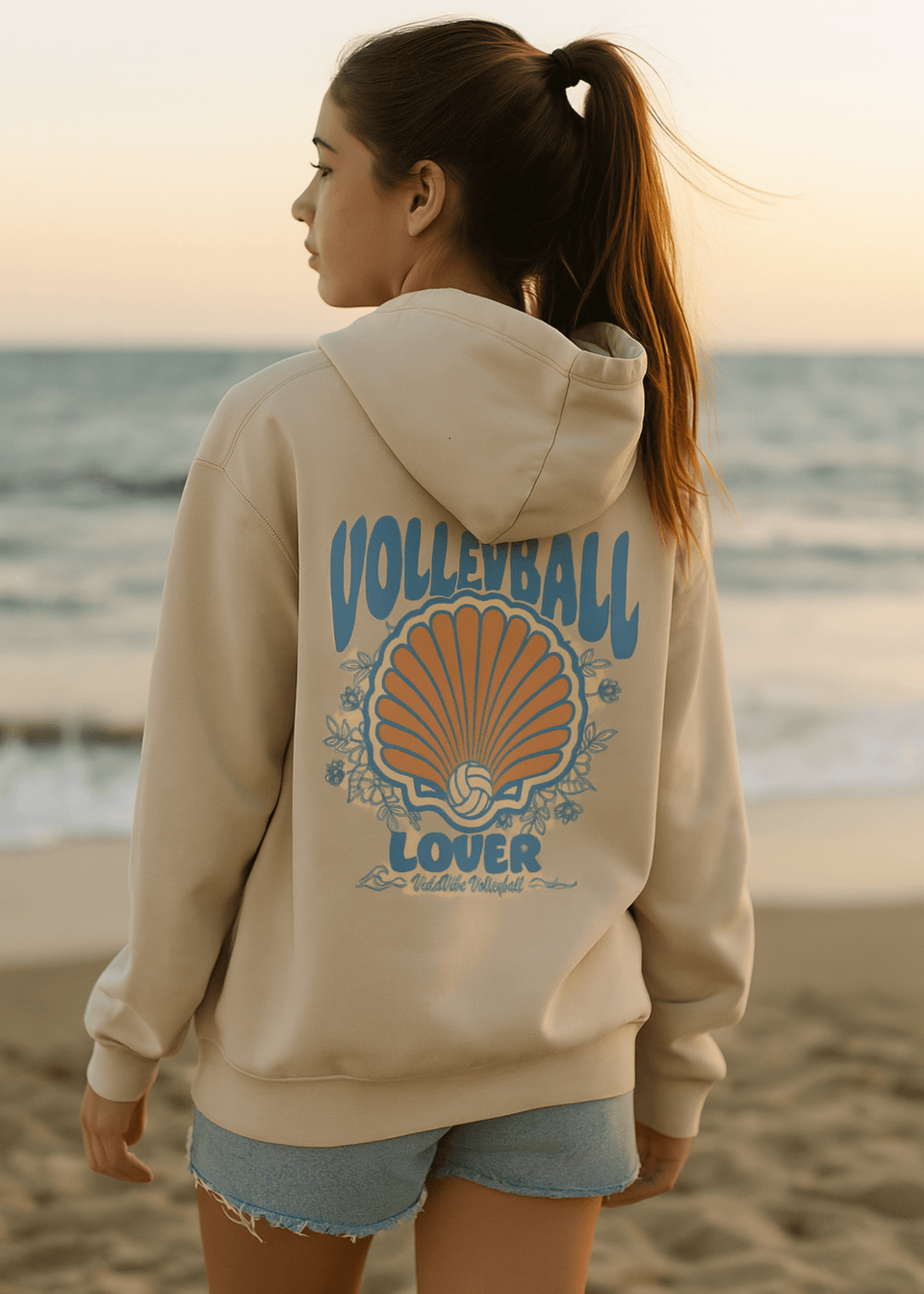 Person wearing a hoodie with 'Volleyball Lover' design on a beach at sunset